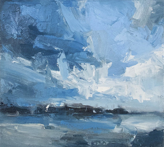 Blue sky and coast with dark hills and grey beach